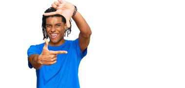 Gündelik kıyafetler giyen, gülümseyen ve mutlu yüzlü elleri ve parmakları olan genç Afro-Amerikan bir adam. yaratıcılık ve fotoğrafçılık kavramı. 