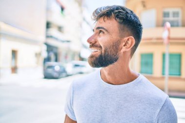 Genç İspanyol adam gülümseyerek şehirde mutlu bir şekilde yürüyor.