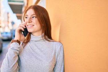 Genç İrlandalı kız gülümsüyor. Şehirdeki akıllı telefondan konuşuyor..