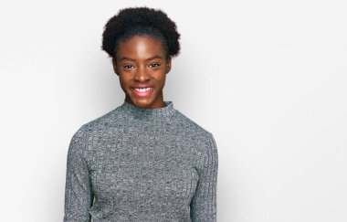 Yüzünde mutlu ve havalı bir gülümseme olan gündelik kıyafetler giyen Afro-Amerikalı genç bir kız. şanslı kişi. 