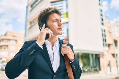 Kafkasyalı genç iş adamı ciddi bir ifadeyle şehirdeki akıllı telefondan konuşuyor..