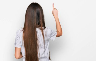 Latin asıllı genç bir kız, günlük beyaz tişört giyiyor. Ters pozlar veriyor. 