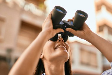 Şehirde dürbünle gülümseyen genç İspanyol kız..