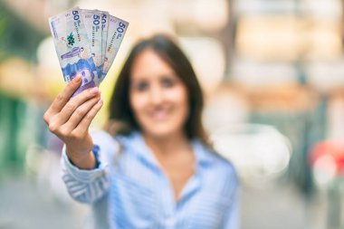 Genç İspanyol kadın gülümseyerek Kolombiya 'ya 50 pezoluk banknot gösteriyor..