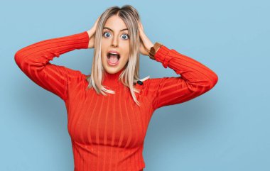 Güzel sarışın kadın sıradan kıyafetler giyiyor çılgın ve elleri başının üstünde korkmuş, şok geçirmekten korkmuş ve ağzı açık kalmış. 