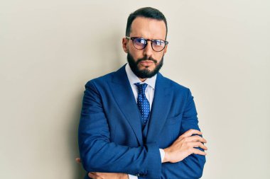 Sakallı, takım elbiseli, kravatlı, kuşkucu ve gergin genç bir adam. Yüzünde çapraz kollarla onaylamayan bir ifade var. negatif kişi. 