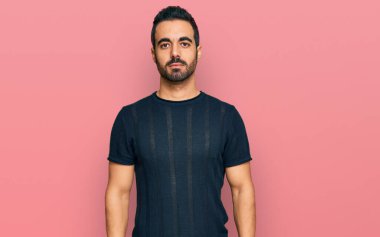 Yüzünde ciddi bir ifade olan günlük kıyafetler giyen genç bir İspanyol. Basit ve doğal bir şekilde kameraya bakıyorsun.. 