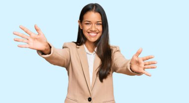 Güzel İspanyol kadın iş ceketi giyiyor kameraya bakıyor sarılmak için kollarını açmış gülümsüyor. Mutluluğu kucaklayan neşeli bir ifade.. 