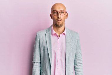 Bald man with beard wearing business clothes and glasses with serious expression on face. simple and natural looking at the camera. 