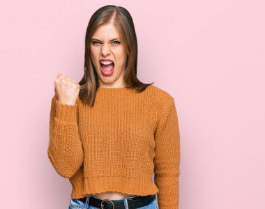 Güzel, beyaz bir kadın, günlük kıyafetler giyiyor kızgın ve kızgın. Öfkeyle bağırırken yumruğunu kaldırıyor. öfke ve agresif konsept. 