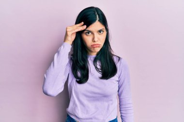 Gündelik kıyafetler giyen genç İspanyol kadın. Alnındaki bir sorun yüzünden endişeli ve stresli. Kriz için endişeli. 