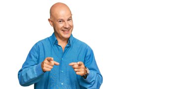 Orta yaşlı kel bir adam, sıradan kıyafetler giyip mutlu ve komik yüzüyle kamerayı işaret ediyor. iyi enerji ve titreşimler. 