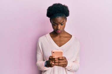 Genç Afro-Amerikalı kız akıllı telefon kullanıyor şüpheci ve gergin, sorun yüzünden surat asıyor. negatif kişi. 