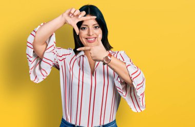 Gündelik kıyafetler giyen, gülümseyen, elleri ve parmakları gülen yüzlü, çerçeveli genç İspanyol kız. yaratıcılık ve fotoğrafçılık kavramı. 