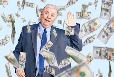 Kıdemli gri saçlı adam iş ceketi giyiyor. Merhaba diyor. Mutlu ve gülümseyen, dostça bir hoş geldin jesti.