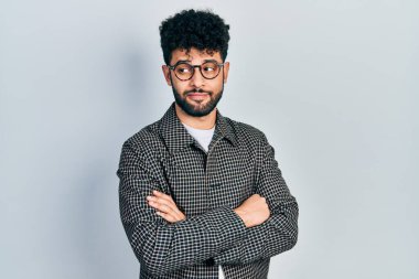 Sakallı, gözlüklü, çapraz hareketli, gülümseyen ve başka yöne bakan genç bir Arap.. 