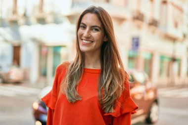 Genç İspanyol kadın gülümseyerek şehirde mutlu mesut dikiliyor..