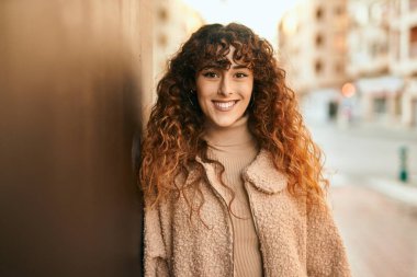 Genç İspanyol kadın gülümseyerek şehirde mutlu mesut dikiliyor.