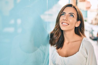 Genç İspanyol kadın gülümsüyor mutlu bir şekilde şehrin duvarına yaslanıyor..