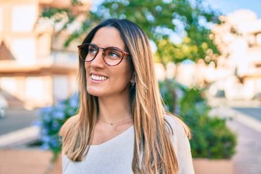 Genç beyaz kadın gülümseyerek şehirde mutlu mesut yürüyor..