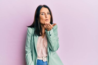 Orta yaşlı esmer kadın, gündelik kıyafetler giyip kameraya bakıyor ve havada el sallayarak öpüşüyor. Güzel ve seksi. aşk ifadesi. 