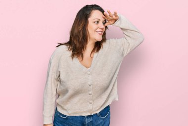 Genç ve cüsseli bir kadın gündelik giysiler giyiyor. Çok mutlu ve gülümsüyor. Çok uzaklara bakıyor. arama kavramı. 