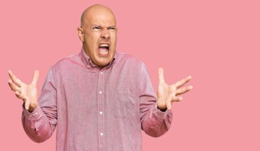 Orta yaşlı, kel, sıradan kıyafetler giyen çılgın ve deli gibi bağıran saldırgan bir ifade ve kollarla bağıran bir adam. hüsran kavramı. 