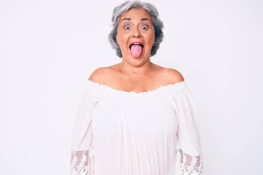 Son sınıf İspanyol asıllı, gri saçlı, günlük kıyafetler giyen, komik bir ifadeyle dilini dışarı çıkaran bir kadın. duygu kavramı. 