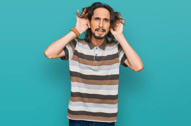Gündelik giysiler giyen genç İspanyol adam iki elini de kulak hareketlerini duymaya çalışıyor. Dedikoduya meraklı. İşitme sorunu, sağır 