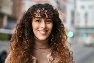 Genç İspanyol kadın gülümseyerek şehirde mutlu mesut dikiliyor.