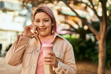 Genç İspanyol kız akıllı telefondan konuşuyor ve şehirde kahve içiyor..