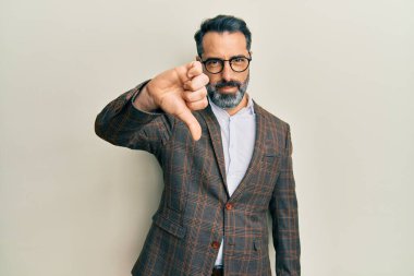 Orta yaşlı, sakallı, gri saçlı, iş ceketi giyen, gözlüklü, mutsuz, kızgın, reddedilmiş ve olumsuz jestli bir adam. kötü ifade. 