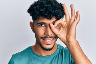 Genç Arap yakışıklı, günlük kıyafetler giymiş, gülümseyen, mutlu, el pençe divan duran, el pençe divan duran. 