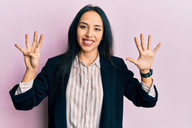 İş kıyafetleri giyen genç İspanyol kız dokuz numarayı gösterip işaret ederken kendinden emin ve mutlu gülümsüyor.. 