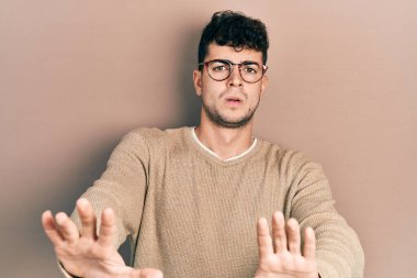 Günlük kıyafetler ve gözlük takan genç İspanyol adam avuçlarıyla jestleri durduruyor, kızgın ve hayal kırıklığına uğramış ifade ediyor. 