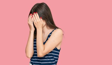 Genç, güzel, beyaz bir kız, günlük kıyafetler ve ağlarken suratını ellerle kapatan üzgün bir ifade takınıyor. depresyon kavramı. 