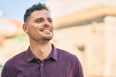 Genç İspanyol adam gülümseyerek şehirde mutlu mesut dikiliyor..