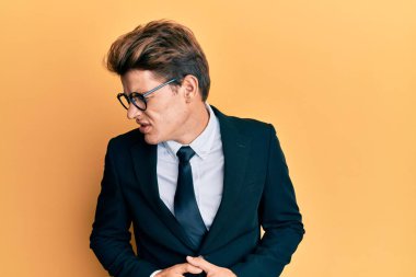 Mide bulantısı, acı verici bir hastalık yüzünden takım elbise giyen ve eli karnında kravat takan yakışıklı beyaz bir adam. Ağrı kavramı. 