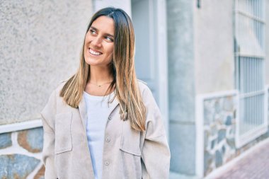 Genç beyaz kadın gülümseyerek şehirde mutlu mesut yürüyor..