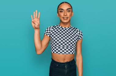 Hispanic transgender man wearing make up and long hair wearing modern clothes showing and pointing up with fingers number four while smiling confident and happy. 