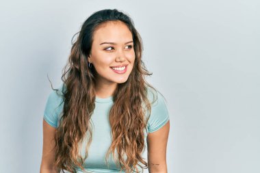 Tişört giyen genç İspanyol kız rahat bir görünüm takınıyor doğal bir yüz ve kendine güvenen bir gülümsemeyle poz veriyor.. 