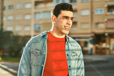 Genç İspanyol adam gülümseyerek şehirde mutlu mesut dikiliyor..