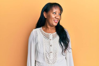 Orta yaşlı Afro-Amerikalı kadın günlük giysiler giyiyor, rahat profil pozu veriyor doğal bir yüzü ve kendine güvenen bir gülüşü var.. 