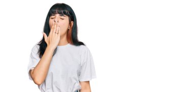 Günlük kıyafetler giyen genç İspanyol kız ağzıyla ağzını kapatmaktan sıkılmış. Huzursuz ve uykulu.. 