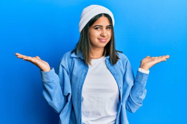 Şirin yün şapkalı genç Latin kadın, hiçbir şeyden habersiz ve kolları açık, hiçbir fikri yok.. 