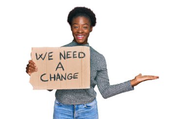 Genç Afrikalı Amerikalı kız elinde bir değişim bayrağına ihtiyacımız var zaferi kutlayan mutlu bir gülümseme ve ellerini kaldırarak kazanan bir ifadeyle 