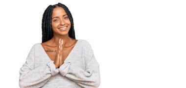 Güzel İspanyol kadın gündelik giysiler giyip ellerle dua ederek af diliyor kendinden emin bir şekilde gülümsüyor.. 