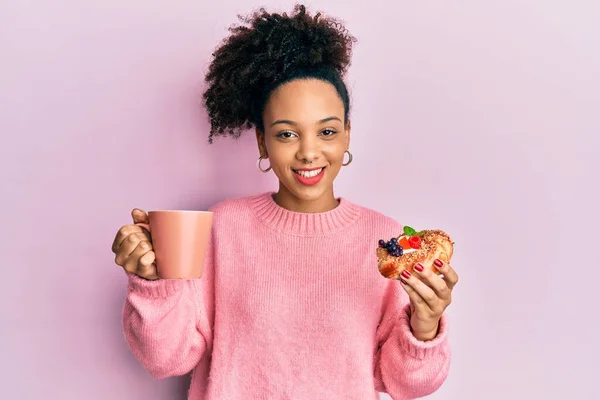 年轻的非洲裔美国女孩喝了一杯咖啡 吃着甜甜的眨眼 带着性感的表情 笑容满面地看着摄像机 — 图库照片