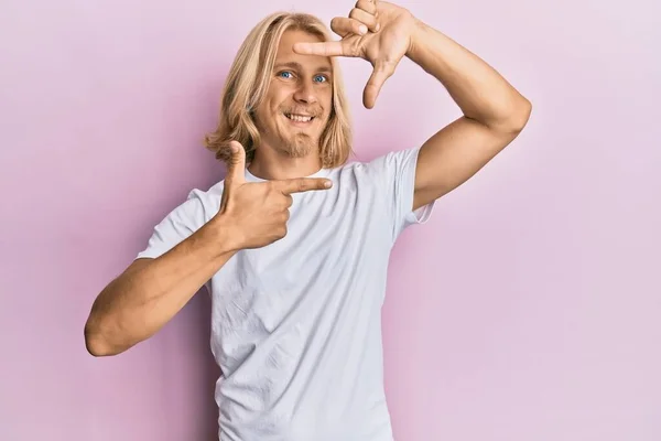 白いカジュアルなシャツを着て長い髪を持つ白人の若い男は 幸せな顔を持つ手や指でフレームを作り笑顔 創造性と写真の概念 — ストック写真