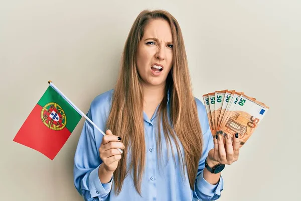 Young Blonde Woman Holding Portugal Flag Euros Banknotes Shock Face — 图库照片